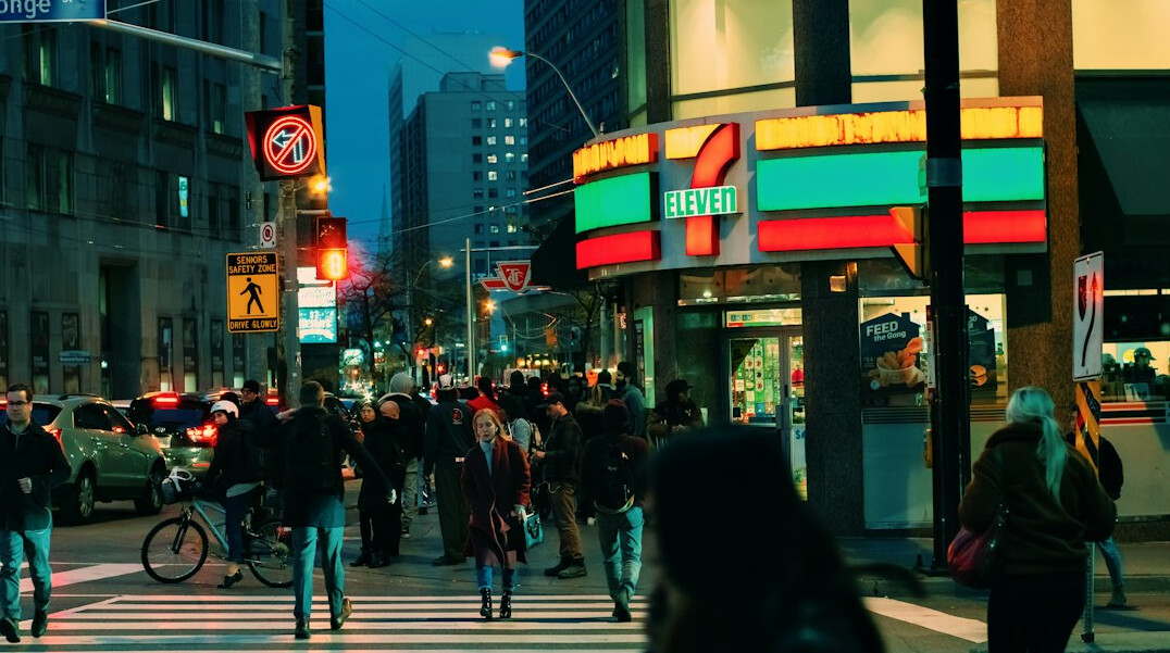 Pedestrians crossing a busy downtown Toronto street at dusk